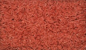 Carne macinata in vaschetta con sfondo grigio, evidenziando il colore poco invitante.